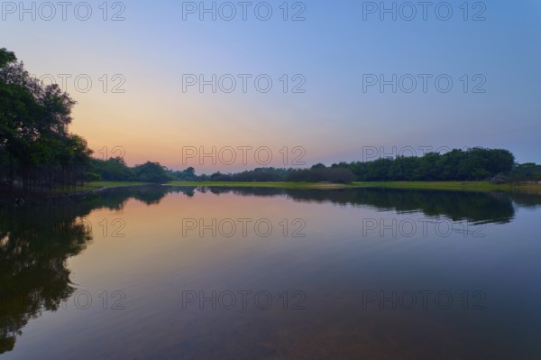 Gentle twilight to a calm lake, with trees on the horizon and blue sky, Fazenda Barranco Alto, Rio Negro, Pantanal, Mato Grosso, Brazil