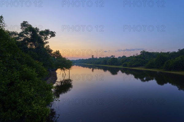 A quiet river morning with shades of blue and orange at sunrise, trees on the shore, Fazenda Barranco Alto, Rio Negro, Pantanal, Mato Grosso, Brazil