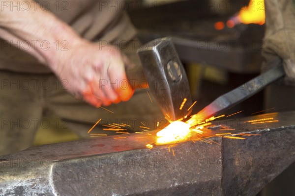 Sparks spray, a blacksmith forging, working at the Ehnert forge in Dresden-Bühlau, Saxony, Germany