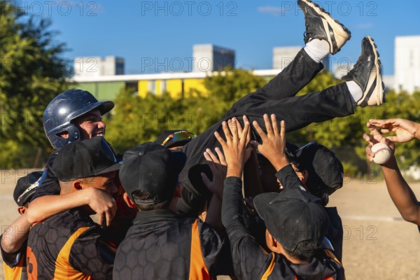 Young baseball teammates lift a smiling boy in celebration after a game, sharing joyful camaraderie and victory on a sunny field during a youth league match