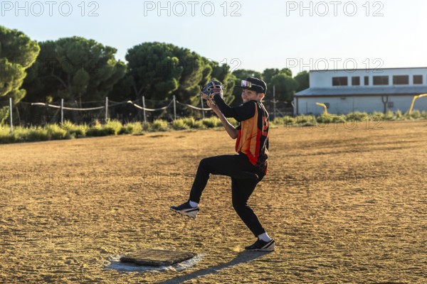 Boy pitching on a dusty baseball field in uniform and sport glasses, smiling as he throws a fast pitch on a sunny afternoon, focused and enjoying youth baseball