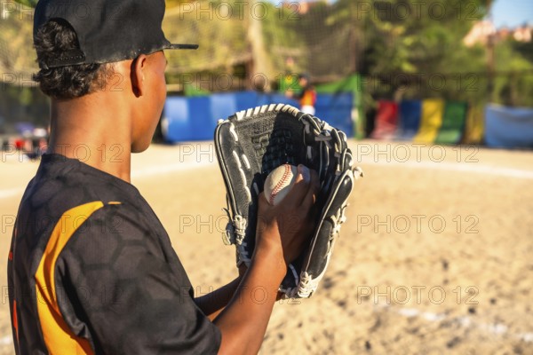 Young baseball player on a sunny field, focused with glove and ball, practicing pitching and catching skills during youth team training and recreational game preparation