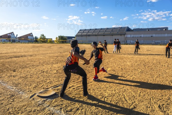 Young baseball players competing in a game on a sunny day, with one player sliding into second base while another fields the play, representing youth sport and outdoor activity