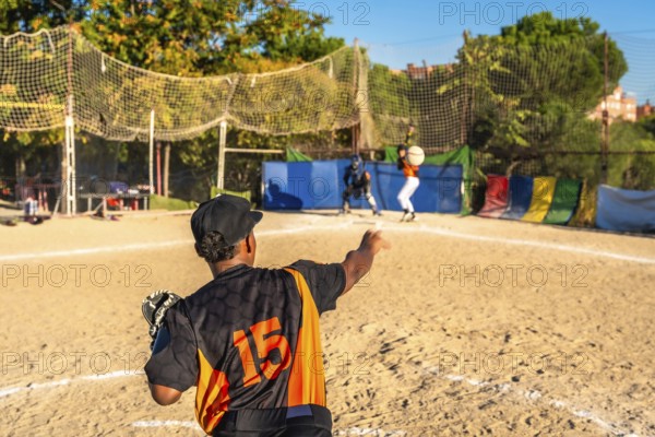 Players on a dusty baseball field engaging in a competitive game, with a pitcher winding up to throw the ball towards the catcher and batter at home plate