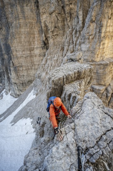 Mountaineer climbs on an exposed rock in the secured via ferrata Bocciere Centrale, Brenta Mountains, Parco Naturale Brenta-Adamello, Trentino, Italy