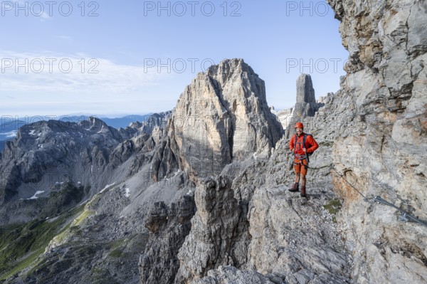 Mountaineer climbs an exposed rock band in the secured Via Ferrata Bocciere Centrale via ferrata, spectacular mountain landscape with steep rocky peaks, Brenta Mountains, Parco Naturale Brenta-Adamello, Trentino, Italy