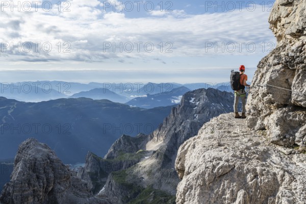 Two mountaineers climb an exposed rock band in the secured Via Ferrata Bocciere Centrale via ferrata, Brenta Mountains, Parco Naturale Brenta-Adamello, Trentino, Italy