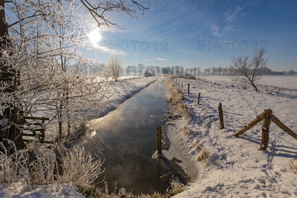 Snowy winter landscape with small river and bright sunshine, Dümmer nature park Park, Lower Saxony, Germany