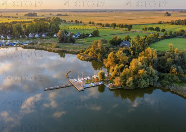 Drone view of Dümmer See with boats in a sailing harbor, surrounded by landscape with fields and holiday homes in the evening light, Dümmer nature park Park, Lower Saxony, Germany