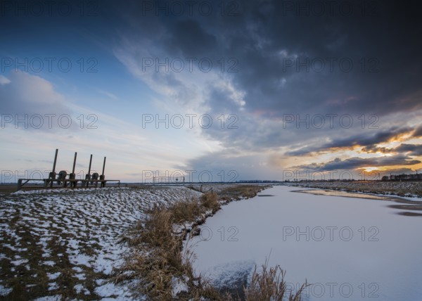 Snowy landscape under dramatic evening sky with clouds on the Hunte near its mouth in Dümmer Lake, Dümmer nature park Park, Lower Saxony, Germany
