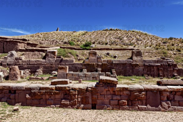 Ancient stone ruins under a clear blue sky surrounded by dry, grassy landscape, The archaeological site with the ruins of Tiwanaku in Bolivia