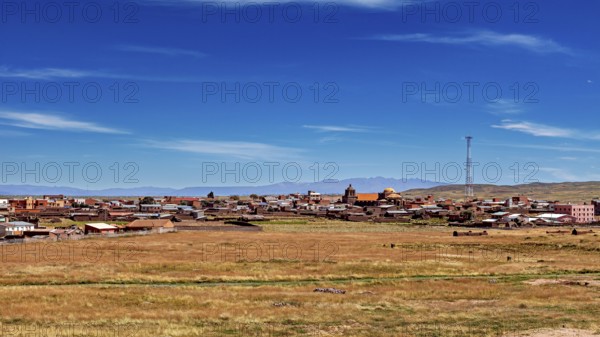 View of a village with church and antenna under wide sky surrounded by open fields, The city of Tiwanaku near the ruins of Tiwanaku in Bolivia