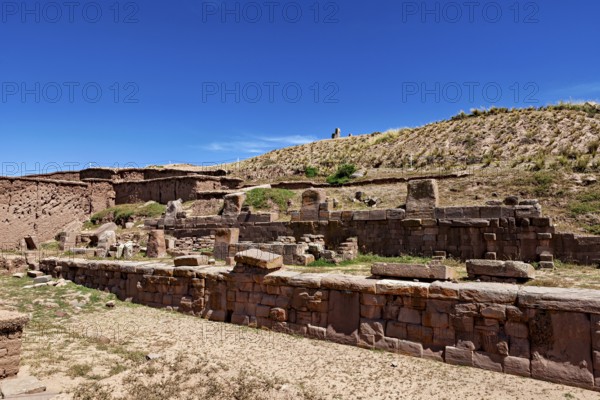 Ancient stone ruin structure against a clear blue sky surrounded by barren landscape and hills, the archaeological site with the ruins of Tiwanaku in Bolivia