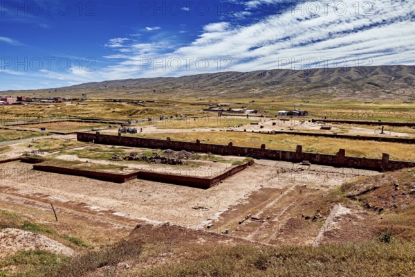 Extensive valley with ruins in the foreground and a mountain range on the horizon, the archaeological site with the ruins of Tiwanaku in Bolivia
