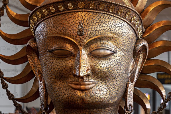 Golden sculpture of a face with solar elements, ancient art style with ornate details, portrait of a goddess in Colombo airport in Sri Lanka