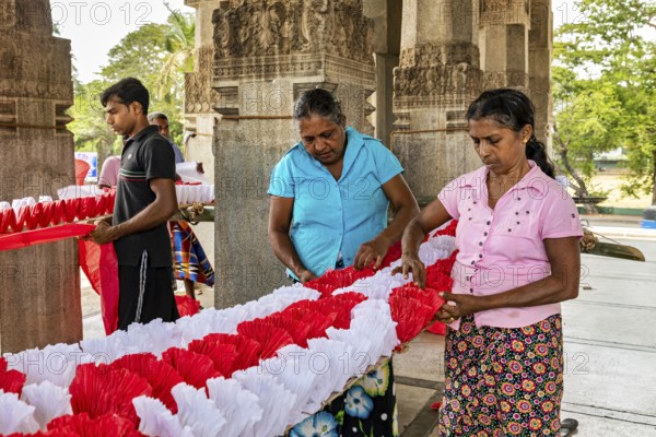 Women making traditional decorations in a temple-like building, people making garlands in Colombo Sri Lanka City Hall