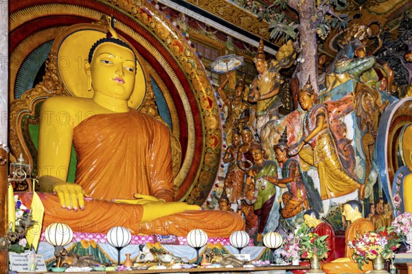 Buddha statue on an altar surrounded by frescoes and religious figures in a spiritual and colorful scene, The Gangaramaya Temple with the Buddha statues in Colombo Sri Lanka