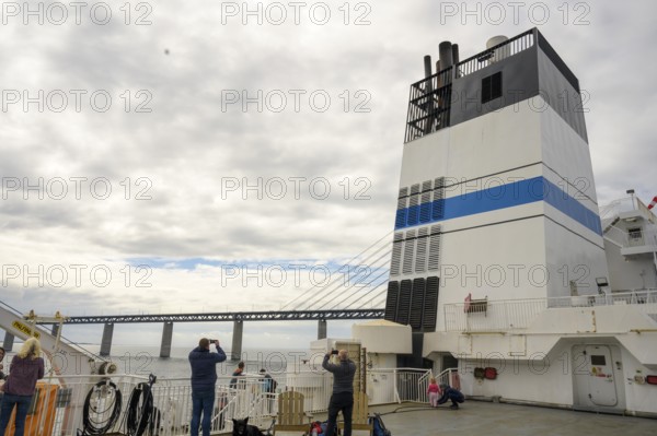 Passengers on a ship with a view of the Øresund Bridge, a ferry under a massive bridge structure of the Öresund Bridge in the background a chimney of the ship, Malmö, Øresund, Skane län, Sweden