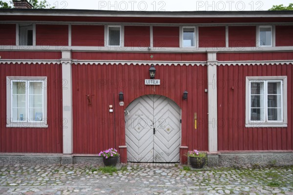 Street scene in the old town of Naantali, red historic wooden building with decorative windows on a paved street, Naanatali, Varsinais-Suomi, Finland