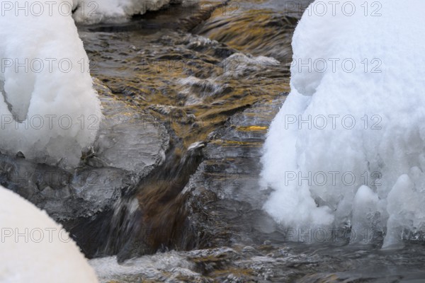 Ilsenburg, Saxony-Anhalt, Germany, close-up of water snaking through icy and snow-covered banks on the Ilse River in the Harz National Park on the Heinrich-Heine Weg Ilsetal hiking trail