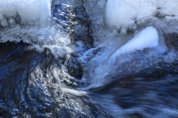 Ilsenburg, Saxony-Anhalt, Germany, Flowing water breaks through thick layers of ice in winter on the Ilse river in the Harz National Park on the Heinrich-Heine trail Ilsetal hiking trail
