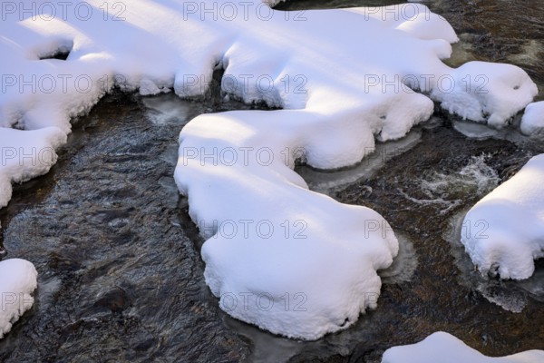 Ilsenburg, Saxony-Anhalt, Germany, Snow-covered ice floes over a flowing stream in winter on the Ilse river in the Harz National Park on Heinrich-Heine trail Ilsetal