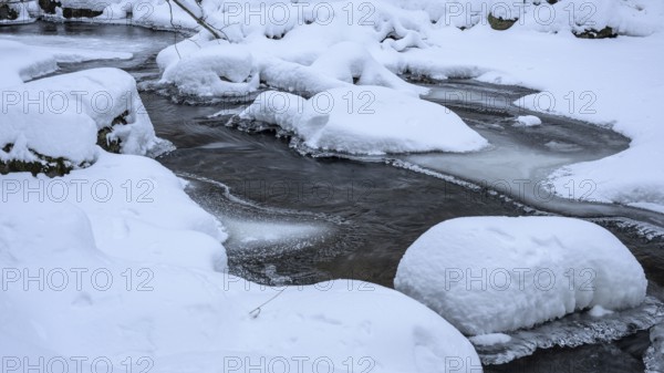 Snowy river Ilse in the Harz National Park with frozen banks in a wintry landscape on the Heinrich-Heine Weg hiking trail Ilsetal, Ilsenburg, Saxony-Anhalt, Germany
