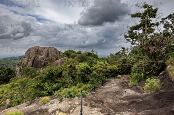 Rocky landscape with cloudy sky and lush green vegetation, a path leads through the scene, The landscape in the mountains near Colombo Sri Lanka