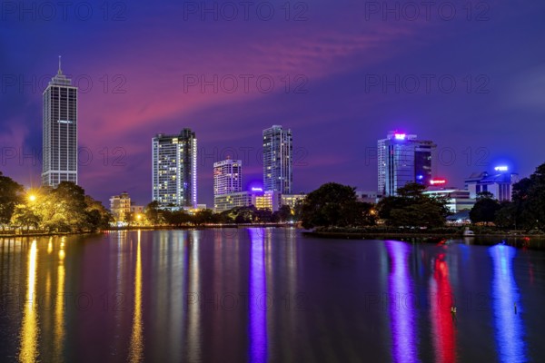 Nighttime city view with brightly lit skyscrapers and colorful sky mirror in the water, the skyline of Colombo Sri Lanka at night
