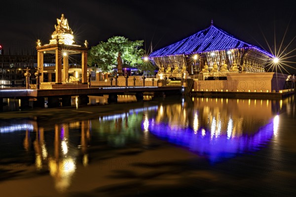 Night scene of an illuminated temple whose lights are reflected in the water, The Seema Malaka Temple with the Buddha statues in Colombo Sri Lanka