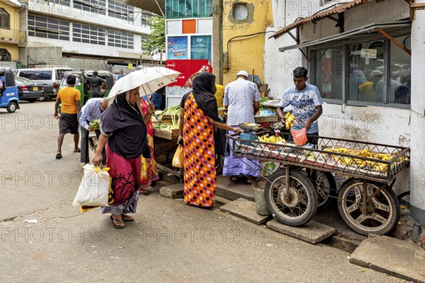 People shop at market stalls in a lively street scene, people on the streets of Slave Island in Colombo Sri Lanka