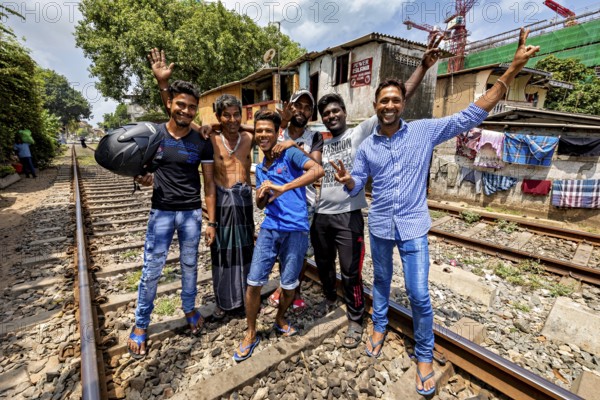 Group of men partying on railroad tracks, showing a gesture and cheerful atmosphere, friends on the railway line in the historic Slave Island district in Colombo Sri Lanka