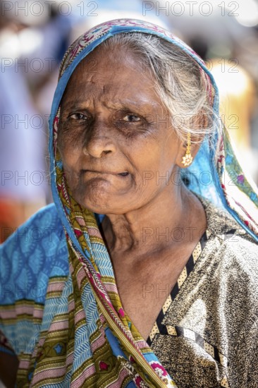 Elderly woman wearing a blue sari with a serious expression and traditional jewelry, portrait of an elderly woman in Colombo Sri Lanka