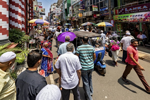 People and rickshaws on a colorful, busy street in the sunshine, in the streets of the old town of Colombo Sri Lanka