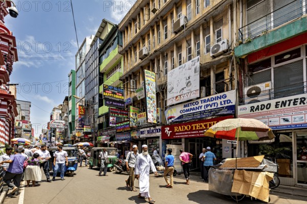 Busy shopping street with lots of people and colorful signs in sunny weather, In the streets of the old town of Colombo Sri Lanka