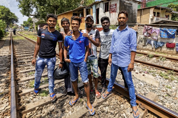 Group of men pose on railroad tracks in an urban setting, showing friendship and smiles, friends on the railway line in the historic Slave Island district of Colombo Sri Lanka