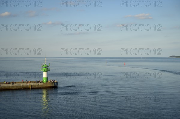 A green lighthouse harbour fire stands on a pier at the port exit of Travemünde in front of a calm, blue sea and a clear sky, Lübeck-Travemünde, Schleswig-Holstein, Germany