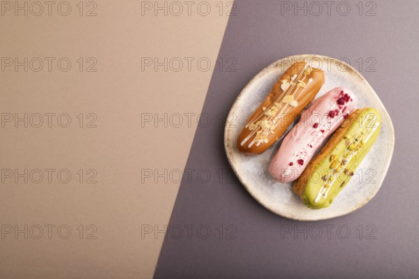 Glazed Eclairs on gray and brown pastel paper background, top view, flat lay, copy space