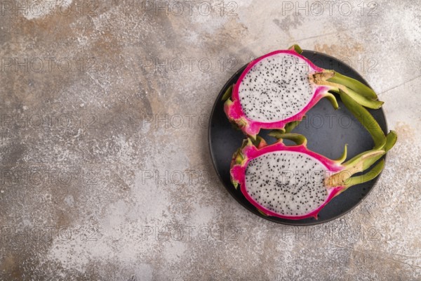 Ripe Pitaya on blue plate on brown concrete background, top view, flat lay, copy space, minimalism