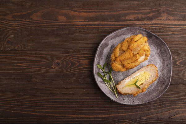 Chicken Schnitzel on gray plate with microgreen on brown wooden background. top view, flat lay, copy space