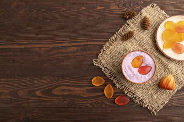 Purple Yogurt, with jelly candy on brown wooden background and linen textile, top view, flat lay, copy space, minimalism