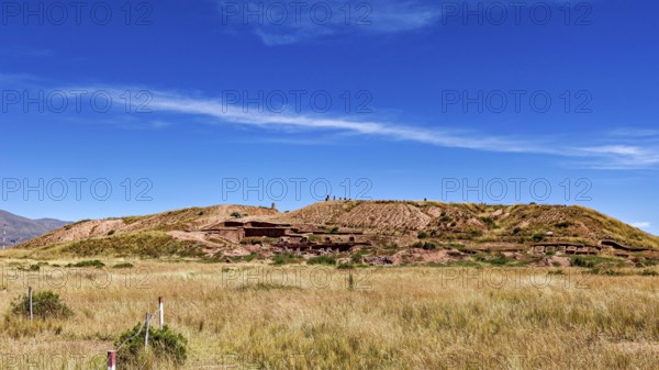 Meadow hill with traces of ruins, under wide blue skies, highlights the natural beauty of the landscape, the archaeological site with the ruins of Tiwanaku in Bolivia