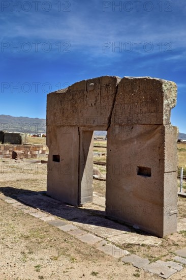 Ancient stone gate in open landscape with mountains and clear sky, The archaeological site with the ruins of Tiwanaku in Bolivia