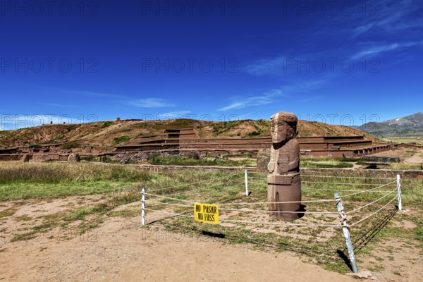 Stone statue in a ruined landscape with a prohibition sign in the foreground, The archaeological site with the ruins of Tiwanaku in Bolivia