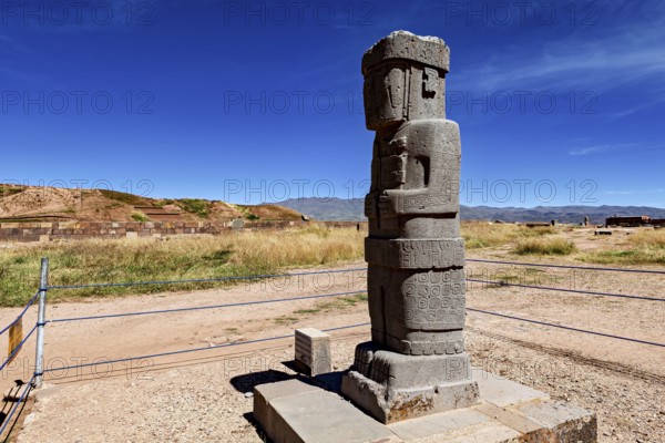 Stone monument with engravings in a wide landscape under blue sky, The archaeological site with the ruins of Tiwanaku in Bolivia