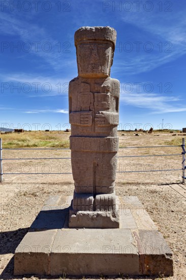 Ancient stone statue on a base in an open-air area under clear skies, The archaeological site with the ruins of Tiwanaku in Bolivia