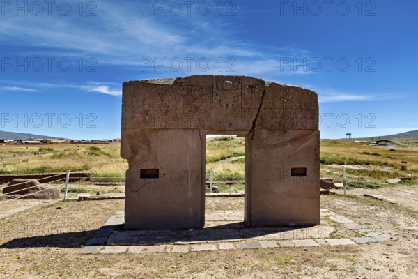 Monumental stone gate on a wide area with blue sky in the background, The archaeological site with the ruins of Tiwanaku in Bolivia