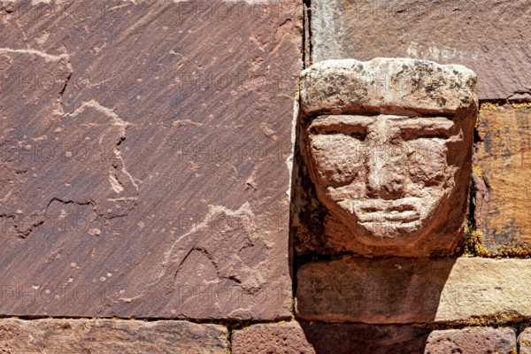 Head engraved in stone in an old wall illuminated by strong sunlight, The archaeological site with the ruins of Tiwanaku in Bolivia