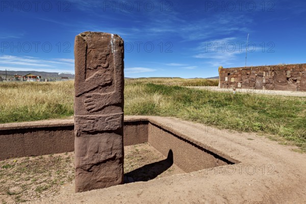 Upright ancient stone column in scenic surroundings under blue sky, The archaeological site with the ruins of Tiwanaku in Bolivia
