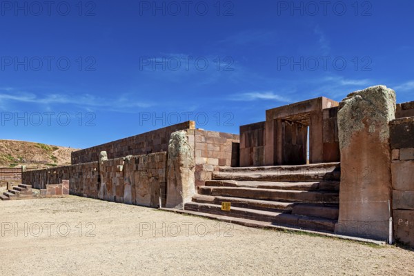 Broad view of ruins with stone entrances and stairs under clear skies, The archaeological site with the ruins of Tiwanaku in Bolivia